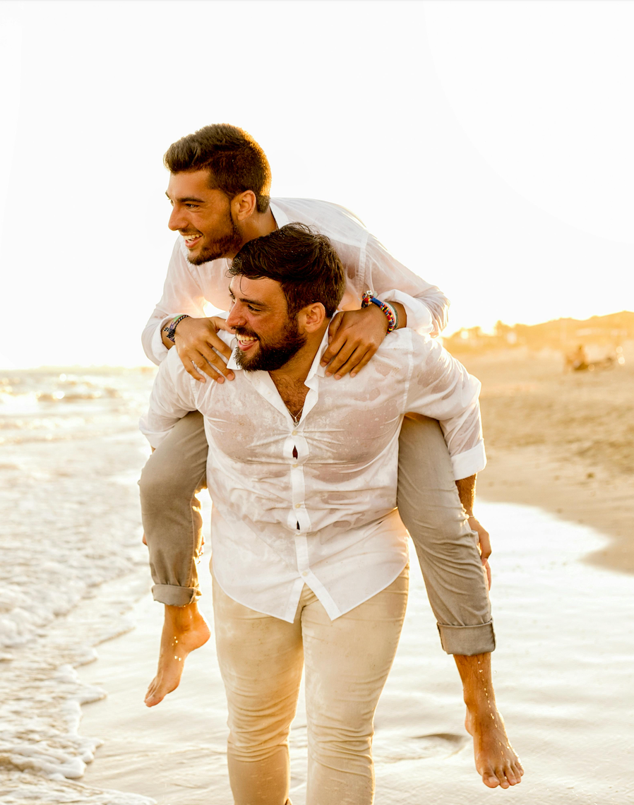 two men in white shirts on the beach