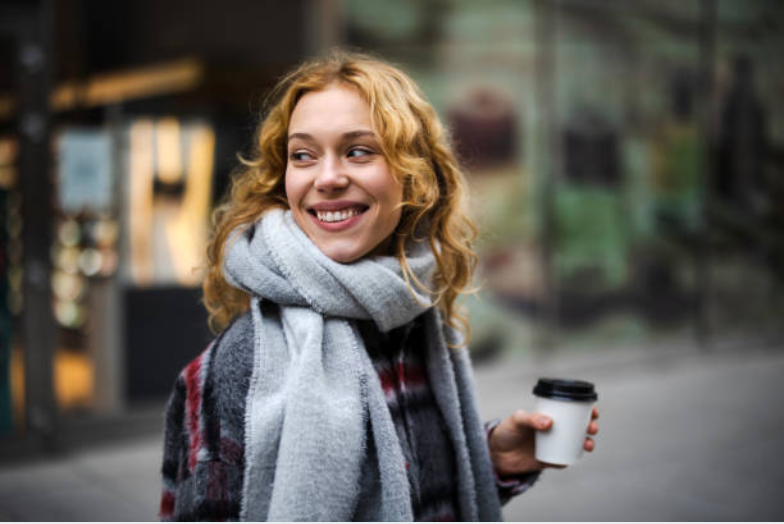 smiling woman holding a take out coffee