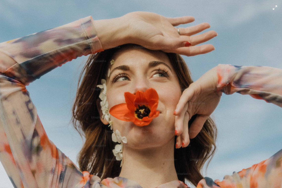 carefree woman holding flower in her mouth