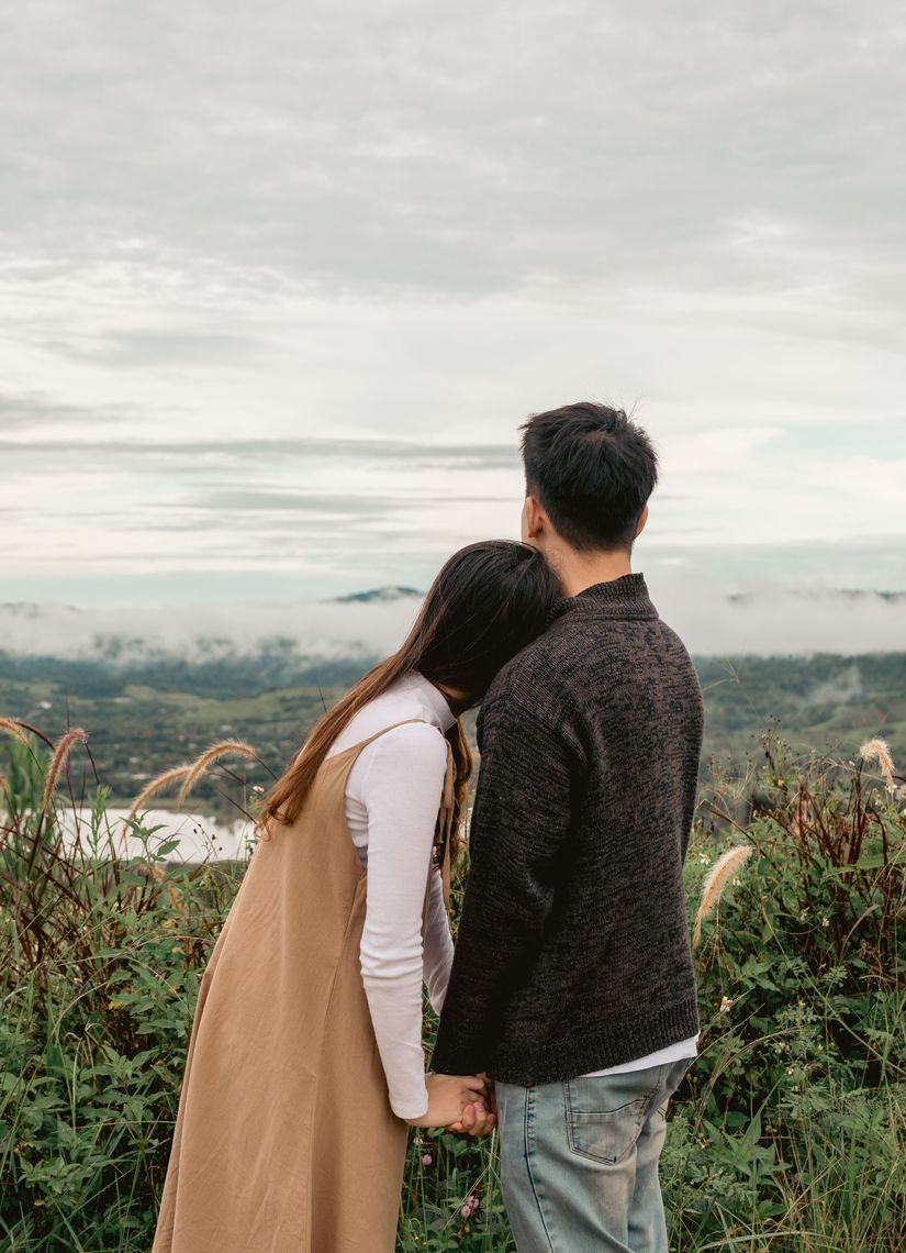 couple holding hands looking over a landscape